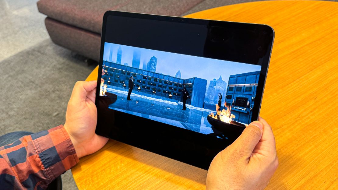 Hands hold an Apple iPad Pro M4 while is playing a rooftop scene from John Wick 4.