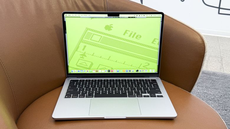 The MacBook Air with a neon green background in a leather chair