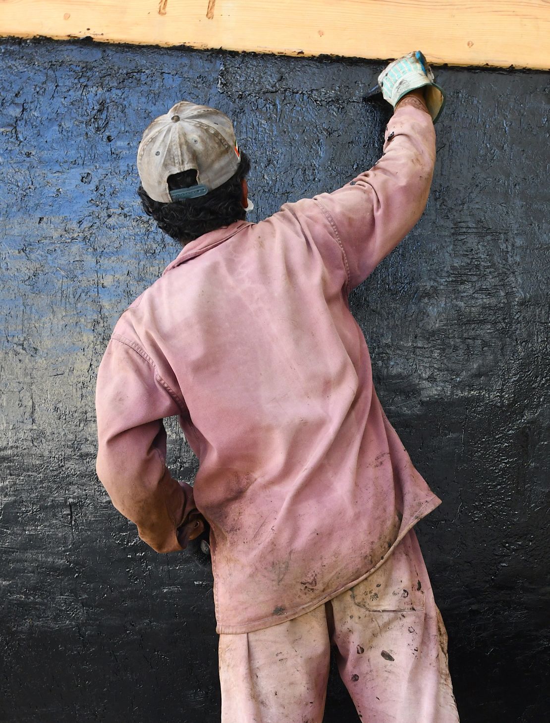 A team member helps to coat the boat with bitumen for waterproofing.