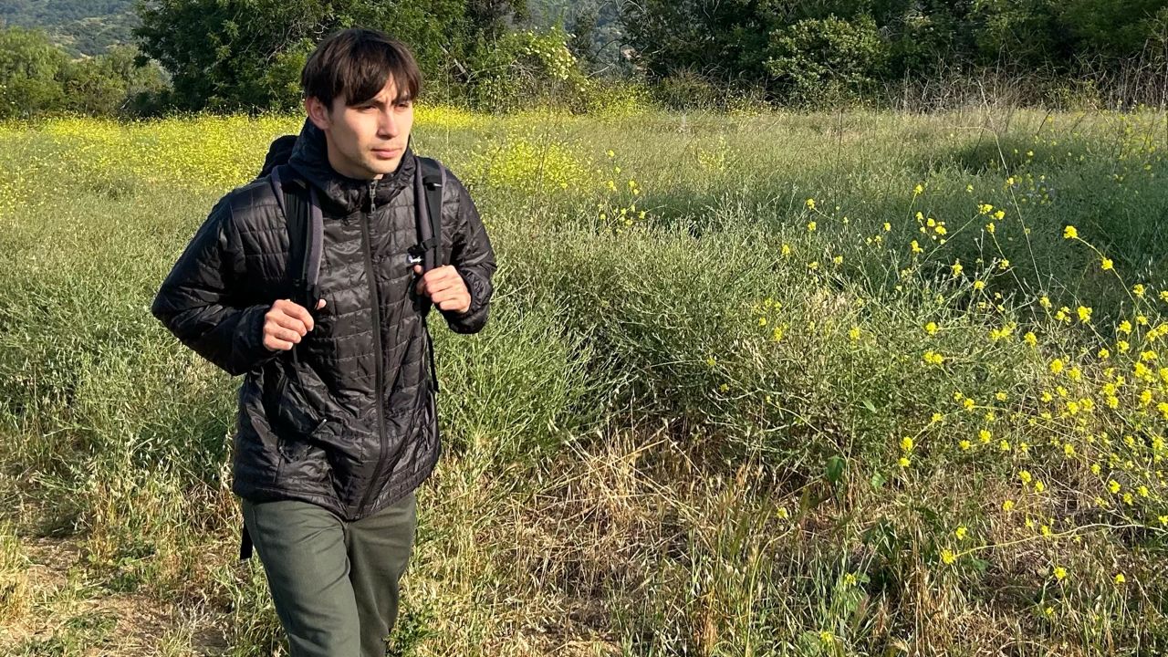Man walking on hiking path wearing black patagonia nano puff hoodie