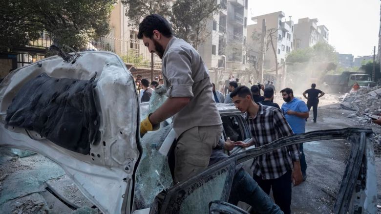 Hombres iraníes trabajan en un vehículo destruido durante los ataques israelíes en Teherán, Irán, el 13 de junio de 2025.