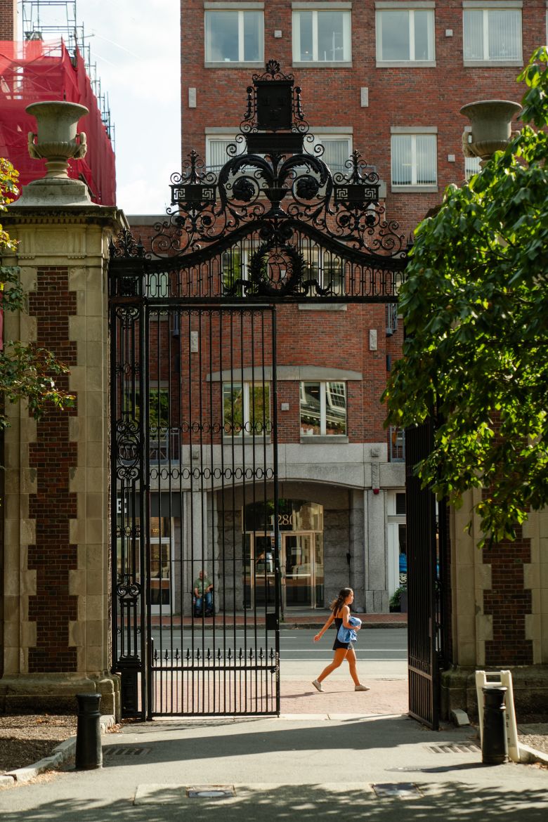 A person walks past Harvard's iron gates Thursday in Cambridge.
