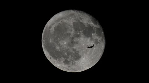 Un avión de pasajeros vuela frente a la luna llena de fresa sobre la bahía de San Francisco vista desde Foster City en California el 22 de junio de 2024.