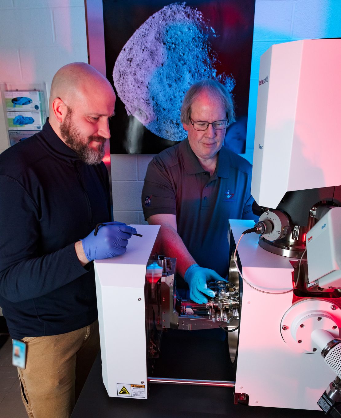 Dr. Tim McCoy, the Smithsonian’s National Museum of Natural History curator of meteorites (center) and Rob Wardell (left), museum specialist of mineral sciences, load a sample into the scanning electron microscope.