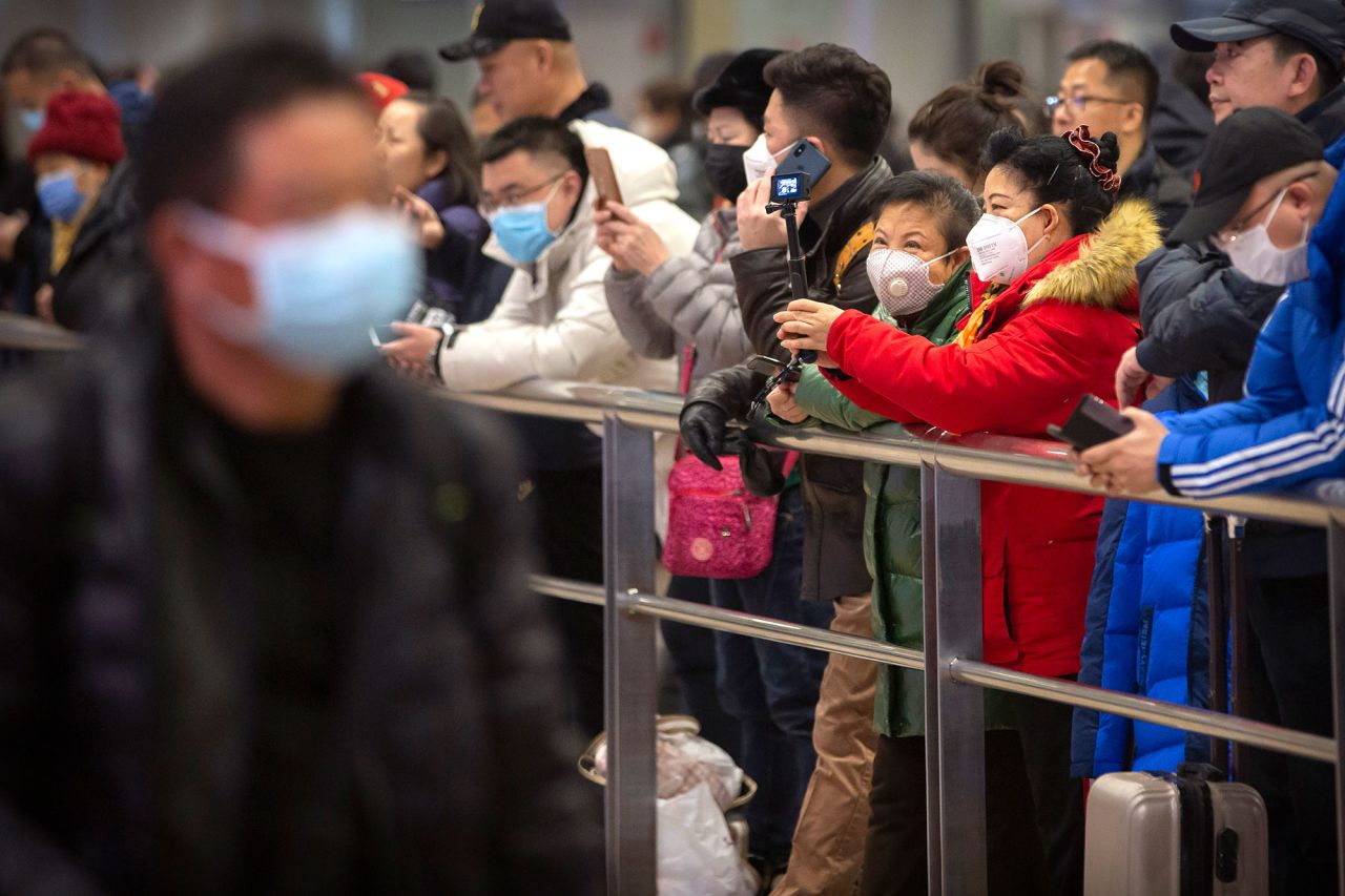 People wear face masks as they wait for arriving passengers at Beijing Capital International Airport in Beijing on January 23.  