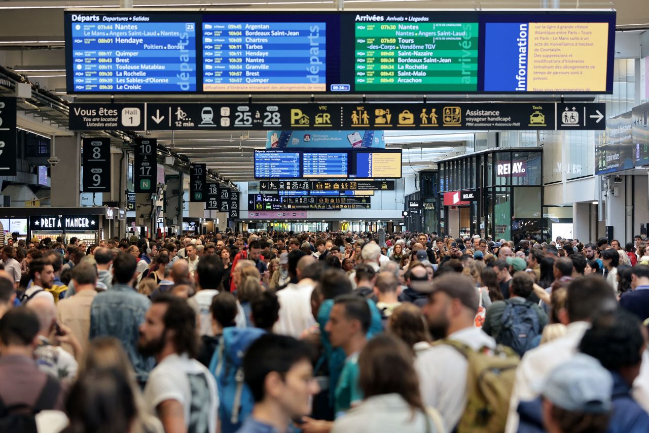 Passengers gather around the departure and arrival boards at the Gare Montparnasse train station in Paris on July 26.