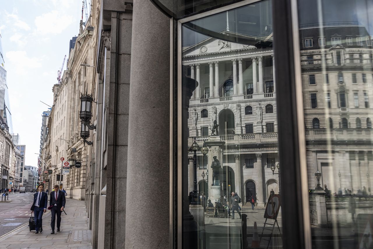 Workers walk past a reflection of the Bank of England on May 11 in London, England.?