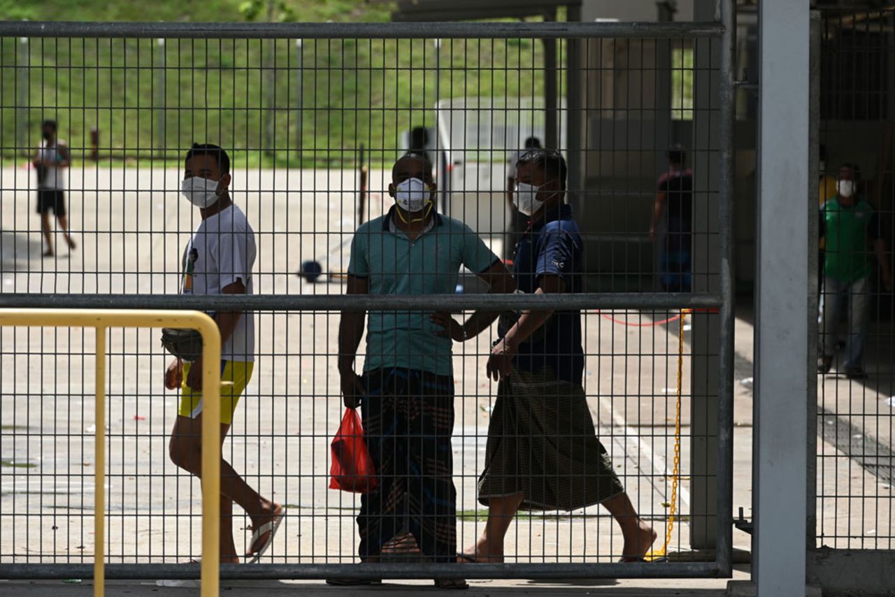 Foreign workers, wearing face masks as a preventive measure against the spread of the coronavirus, look out from the fence of the workers' dormitory in Singapore on April 9.