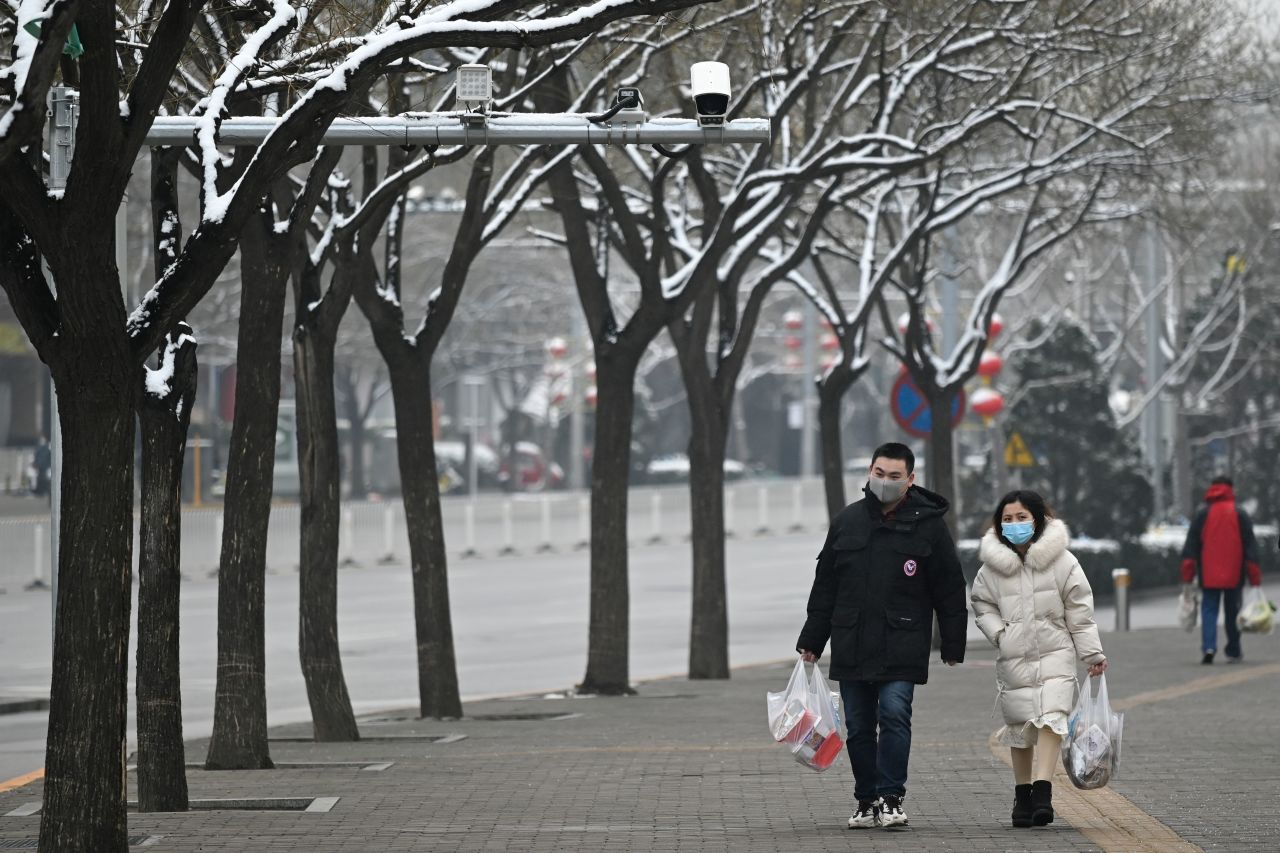 Pedestrians wearing masks walk along a road in Beijing on?Sunday.