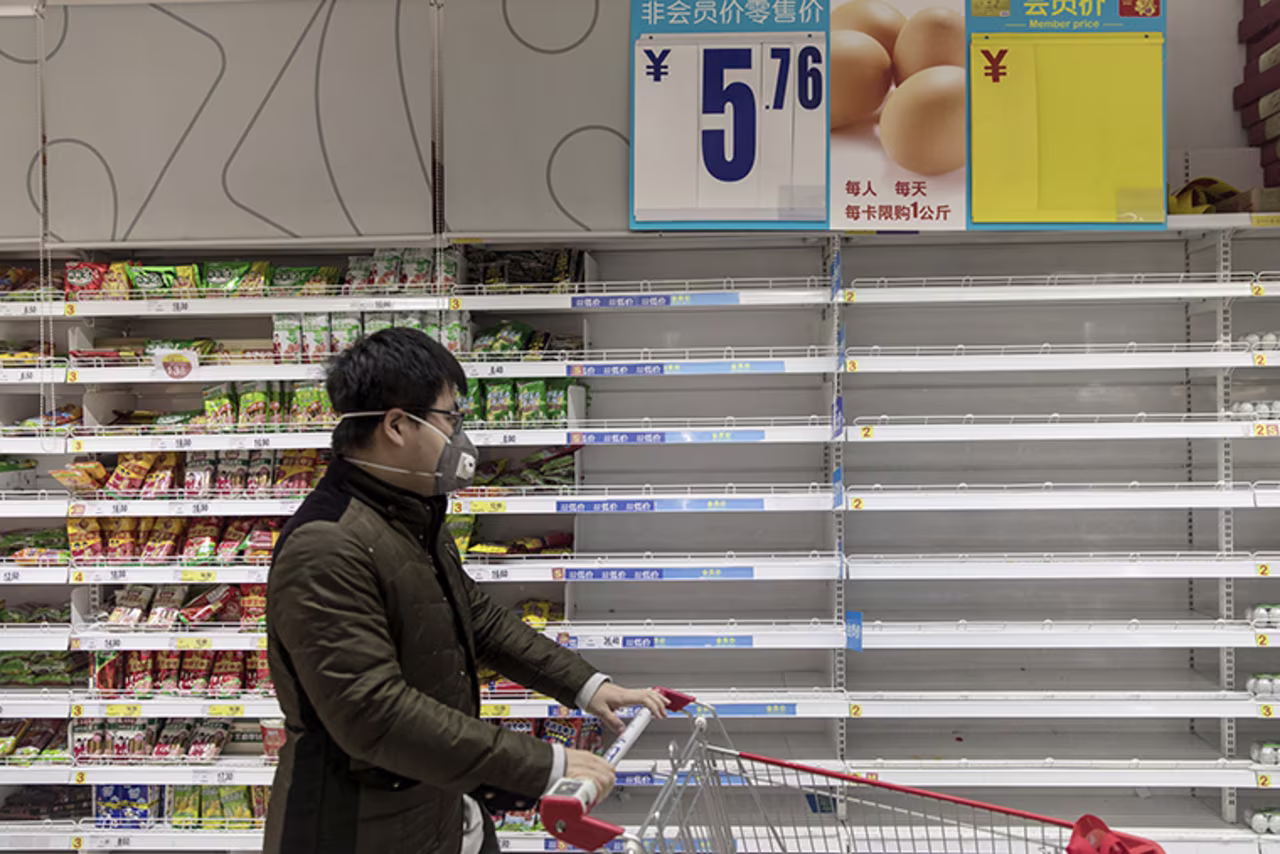 A customer pushes a cart past empty egg shelves at a supermarket in Shanghai, China, on Tuesday, January 28.