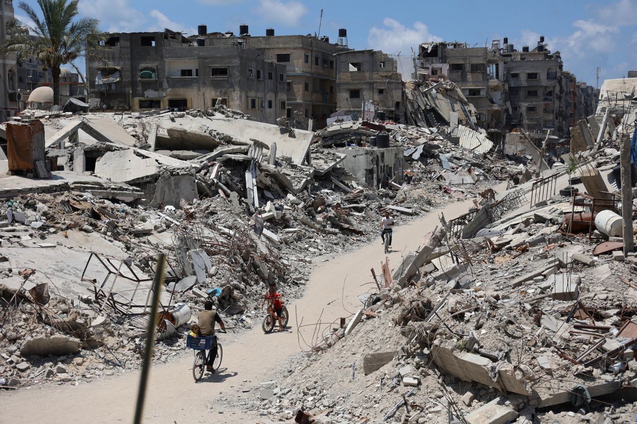 Palestinians cycle past destroyed buildings leveled in a previous Israeli military bombardment of Beit Lahia, Gaza, on Monday, July 29. 