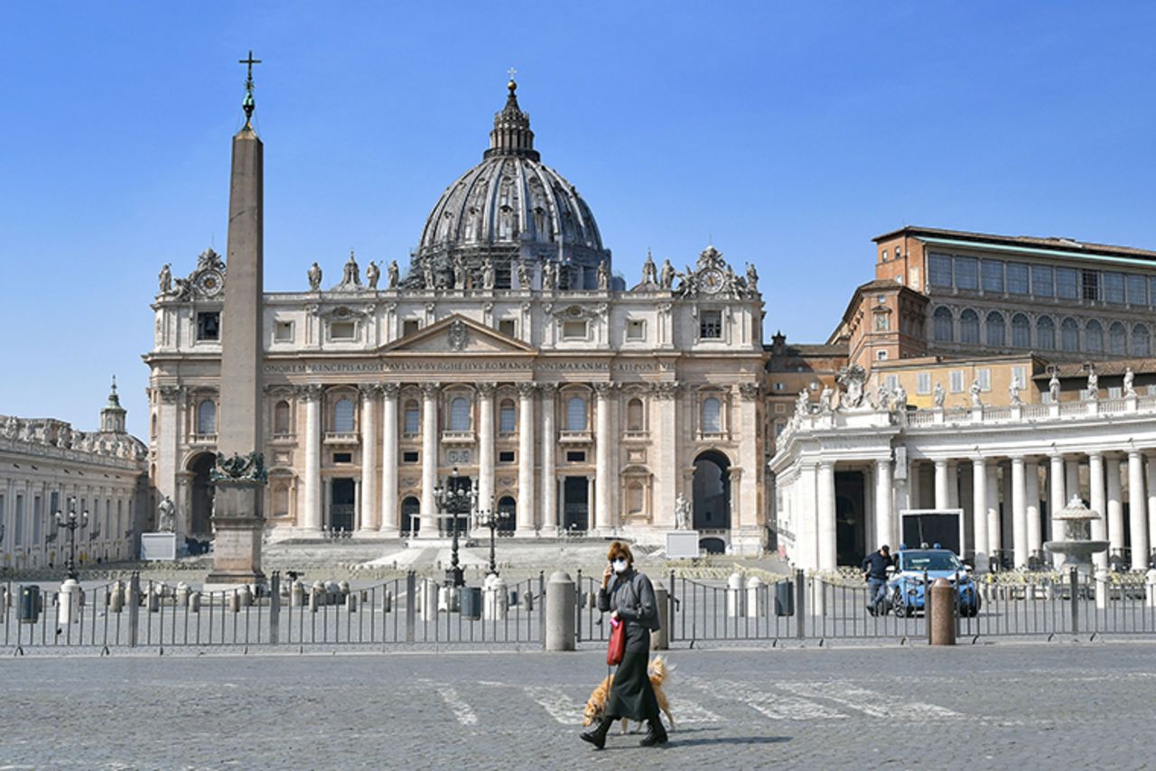 A woman,walks past the empty Saint Peter's square on Sunday, March 22, 2020 at the Vatican. 