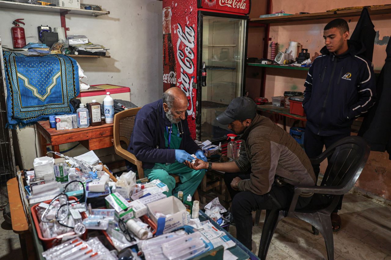 Zaki Shaheen, a retired nurse who turned his shop into a clinic to help displaced Gazans, treats a wounded man at his makeshift clinic in Rafah, Gaza, on January 10.