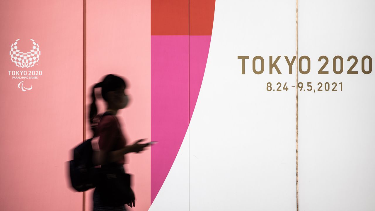  A woman wearing a face mask walks past a display promoting the 2020 Olympics on July 14 in Tokyo. 