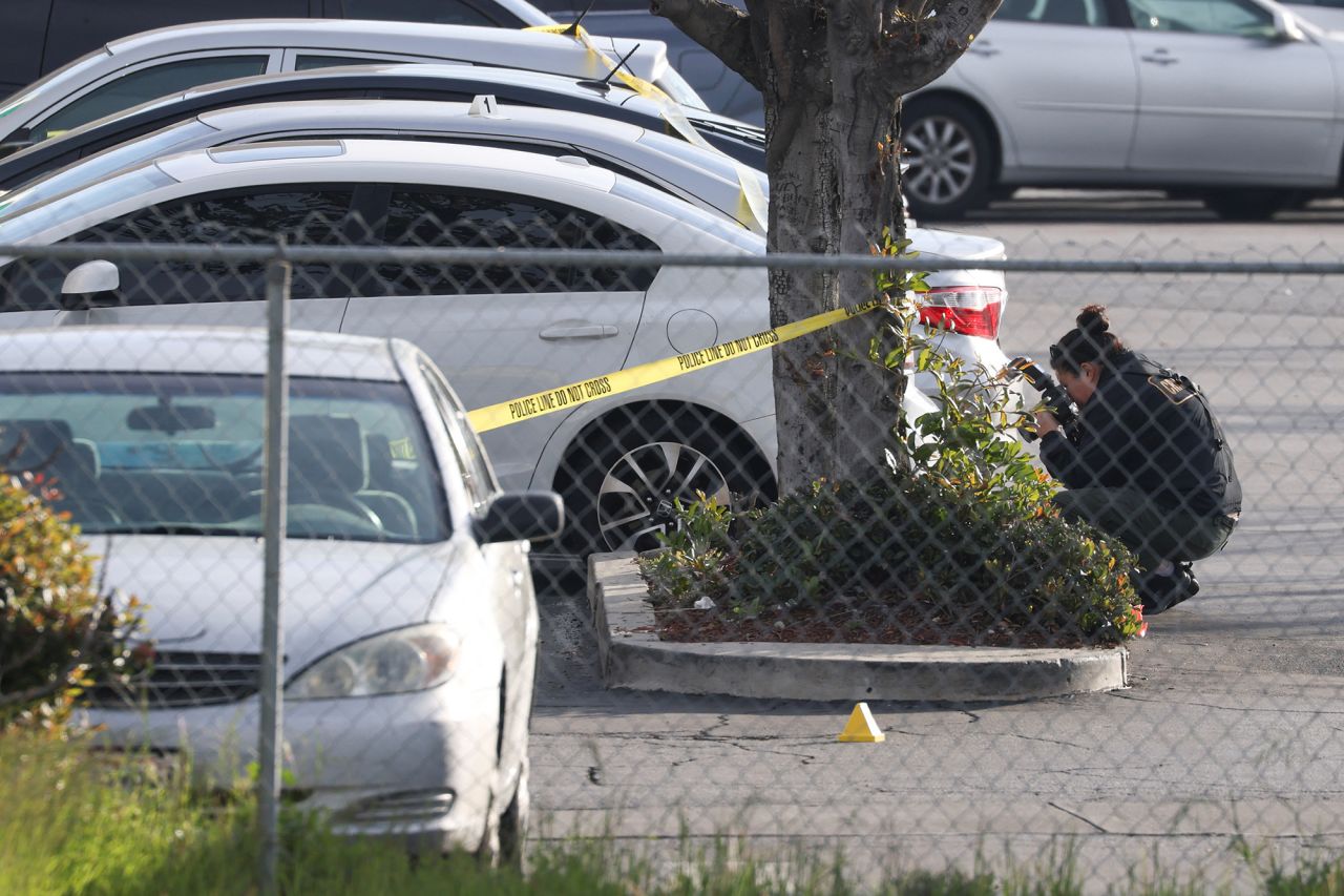 An investigator photographs a parking lot outside the dance studio.