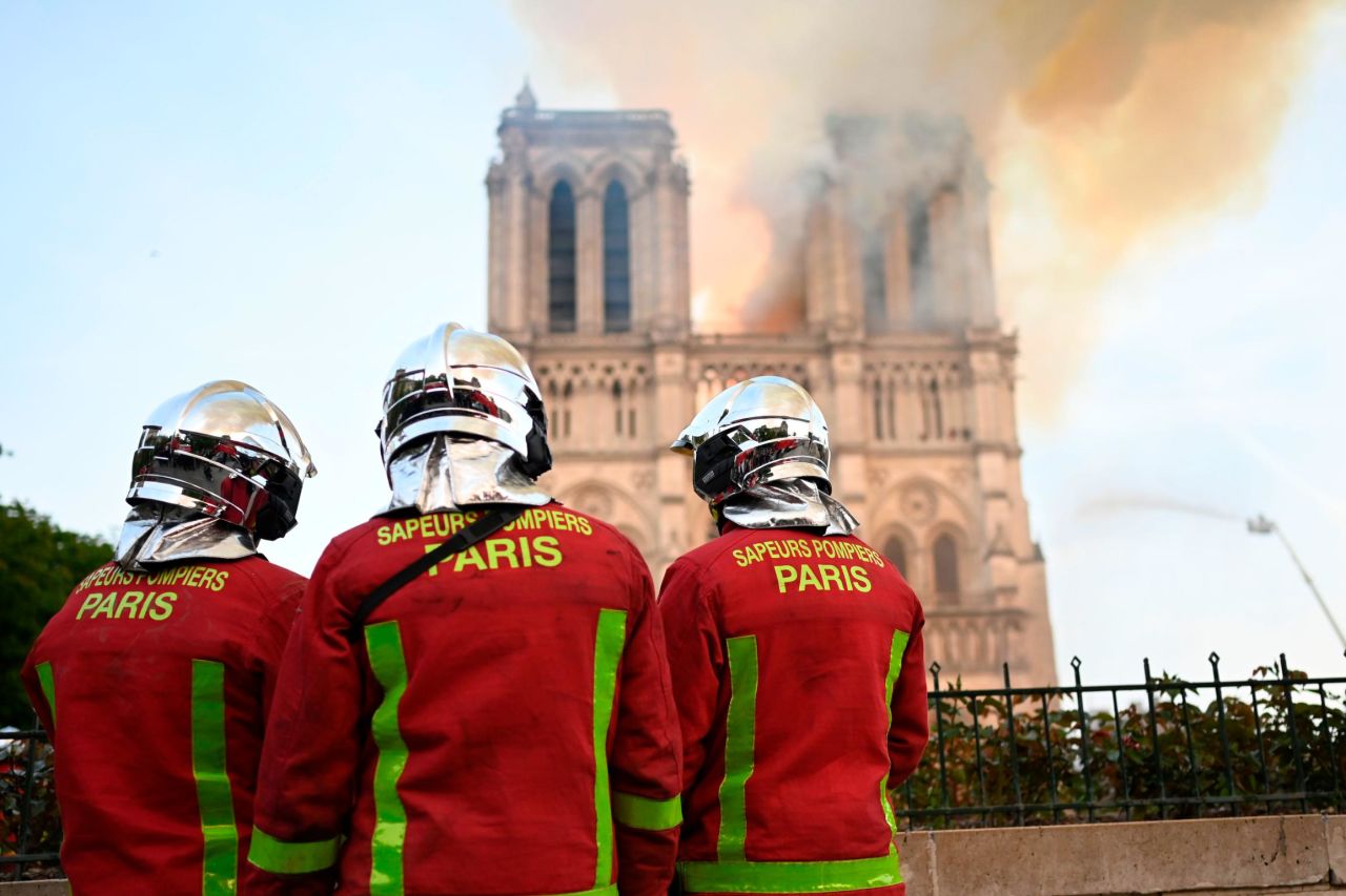 Firefighters stand near the fire. 