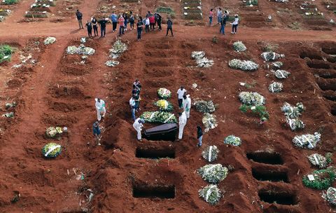 Cemetery workers wearing protective gear lower the coffin of a person who died from complications related to COVID-19 into a gravesite at the Vila Formosa cemetery in Sao Paulo, Brazil, Wednesday, April 7. 