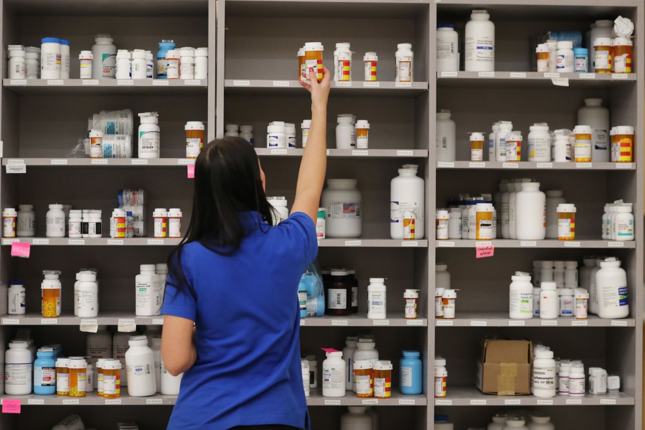 A pharmacy technician grabs a bottle of drugs off a shelve at a pharmacy in Utah.