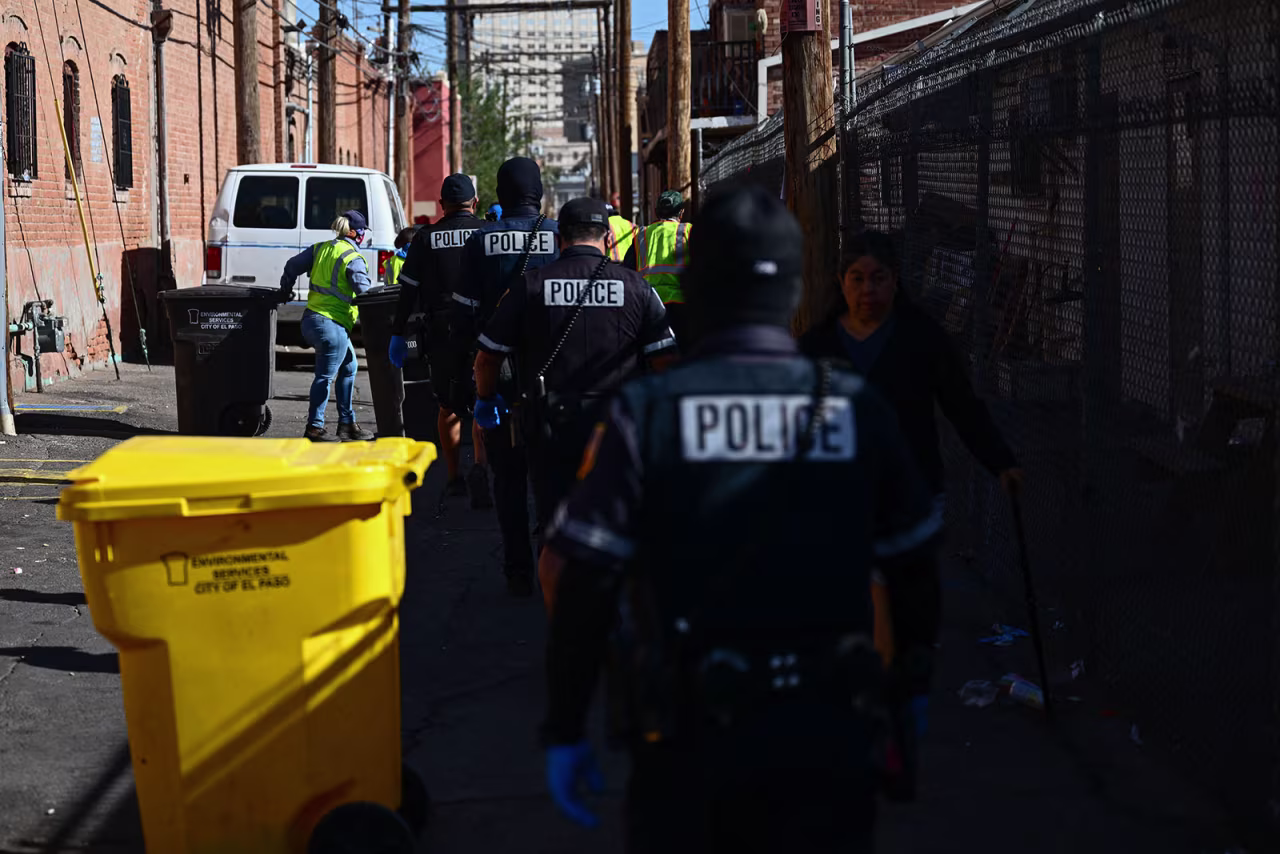 El Paso City Police and sanitation workers clear trash, blankets, and bedding that were left behind from a migrant encampment in an alley near the Sacred Heart Church in downtown El Paso, Texas, on Thursday.