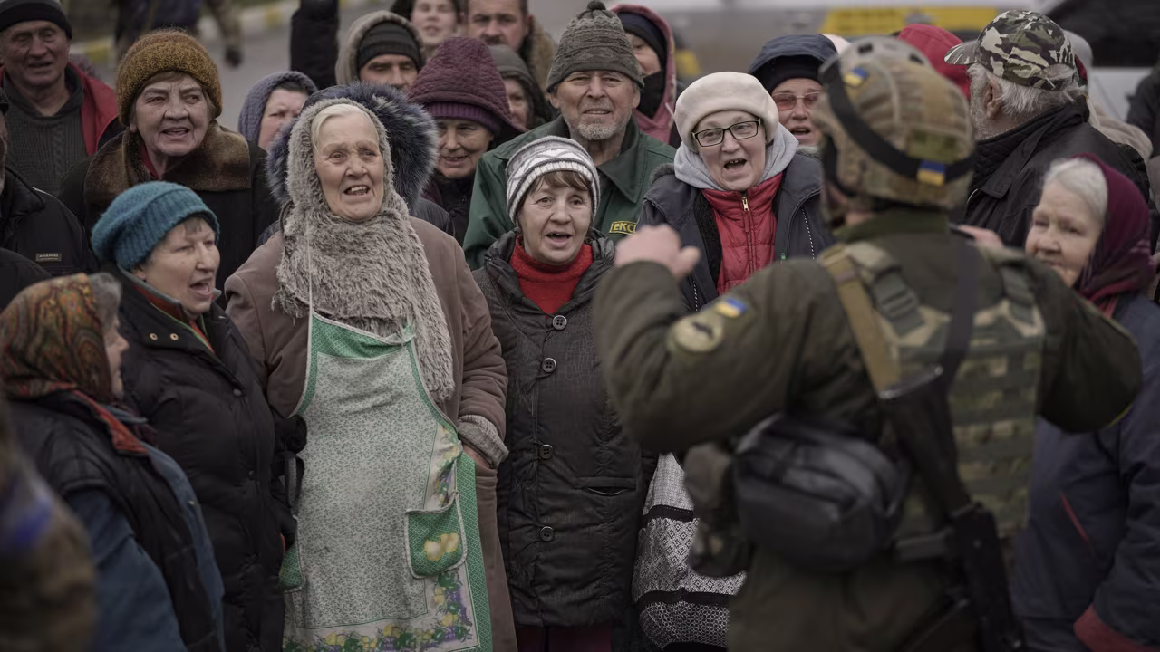 Civilians cheer along with a Ukrainian serviceman as a convoy of military and aid vehicles arrives in the formerly Russian-occupied Kyiv suburb of Bucha, Ukraine on Saturday, April 2.
