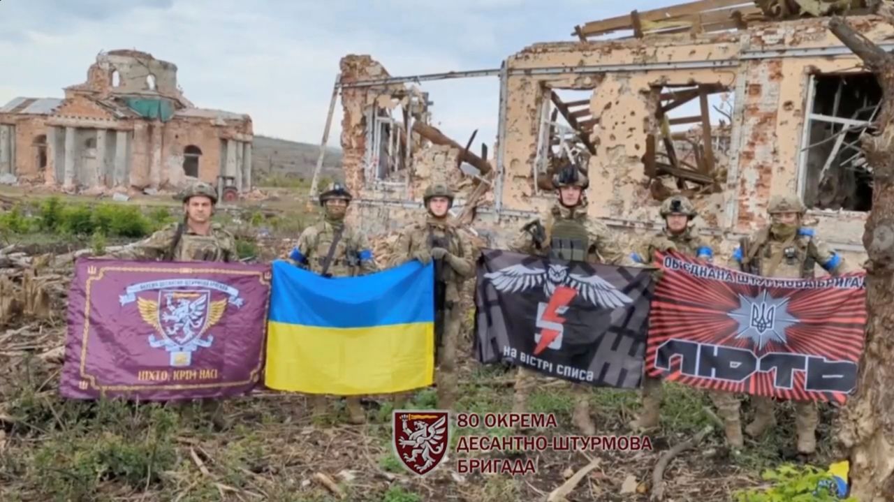 Soldiers hold flags as they speak in front of destroyed buildings in Klishchiivka, Ukraine, as seen in this screen grab taken from a video released on September 17. 