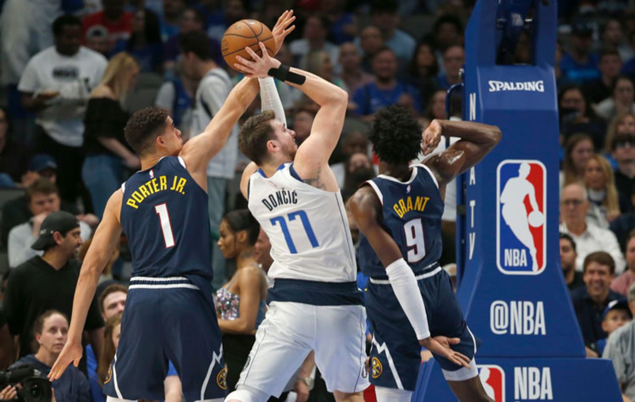 Dallas Mavericks guard Luka Doncic (77) shoots as Denver Nuggets forwards Michael Porter Jr. (1) and Jerami Grant (9) defend during the first half of an NBA basketball game Wednesday, March 11 in Dallas. 