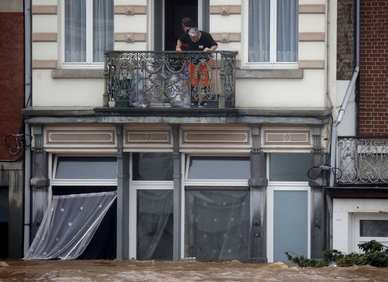 Rescue workers look down from a balcony as floodwaters run down a main street in Pepinster, Belgium, on Thursday.