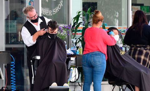 Hairdressers work on customers outdoors in Los Angeles on Friday, August 28.