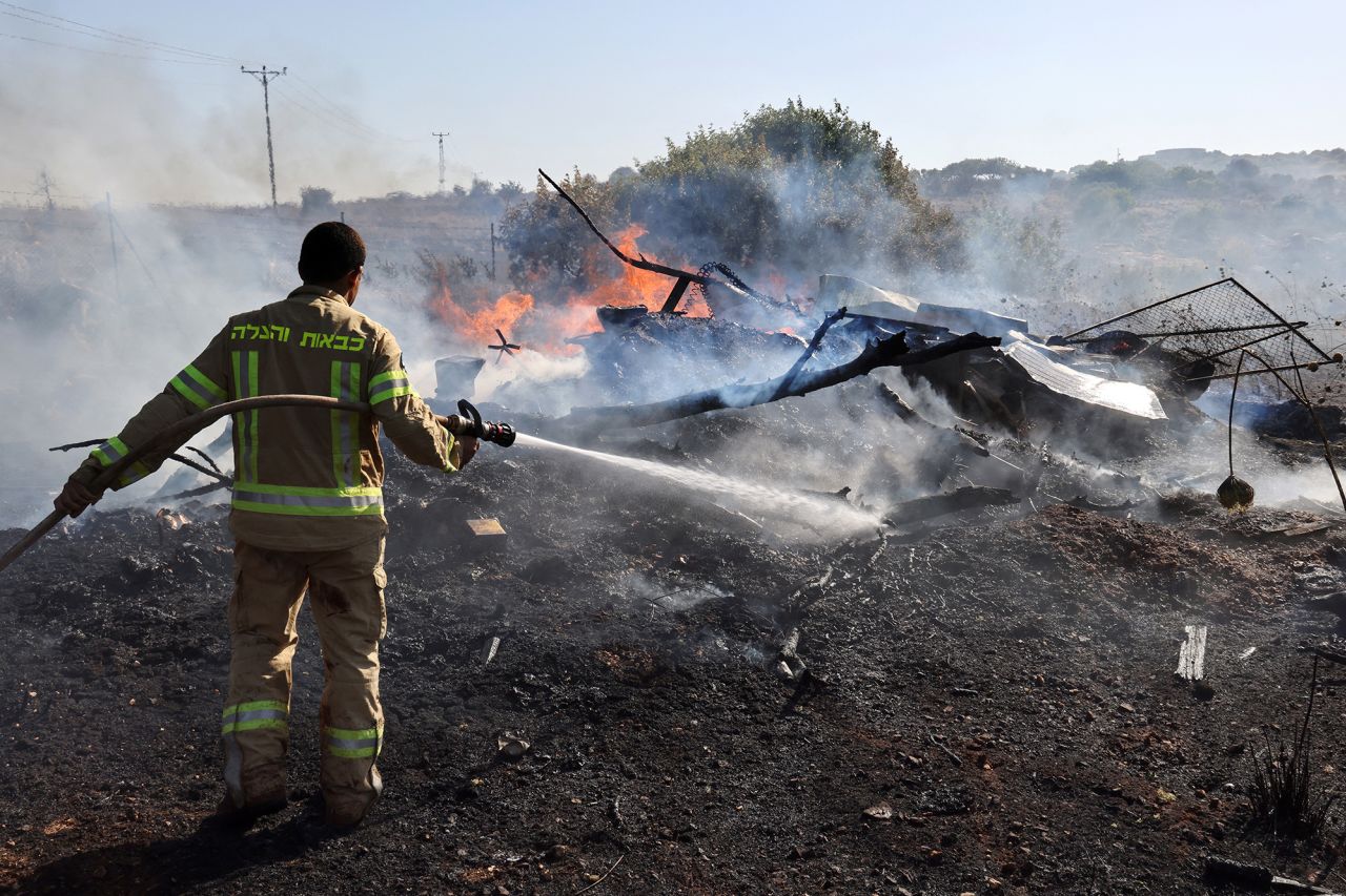 A firefighter puts out flames after rockets launched from Lebanon landed on the outskirts of Kiryat Shmona, Israel, on June 4. 