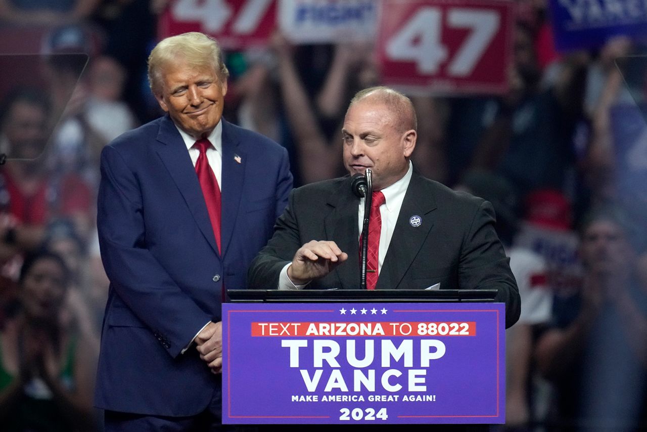 The president of the Arizona Police Association, Justin Harris, right, pauses while speaking as Republican presidential nominee former President Donald Trump listens at a campaign rally in Glendale, Arizona on August 23.