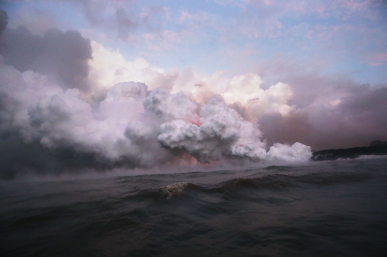 Steam plumes rise as lava glows as it enters the Pacific Ocean at dawn, after flowing to the water from a Kilauea volcano fissure, on Hawaii's Big Island on May 22, 2018 near Pahoa, Hawaii.?