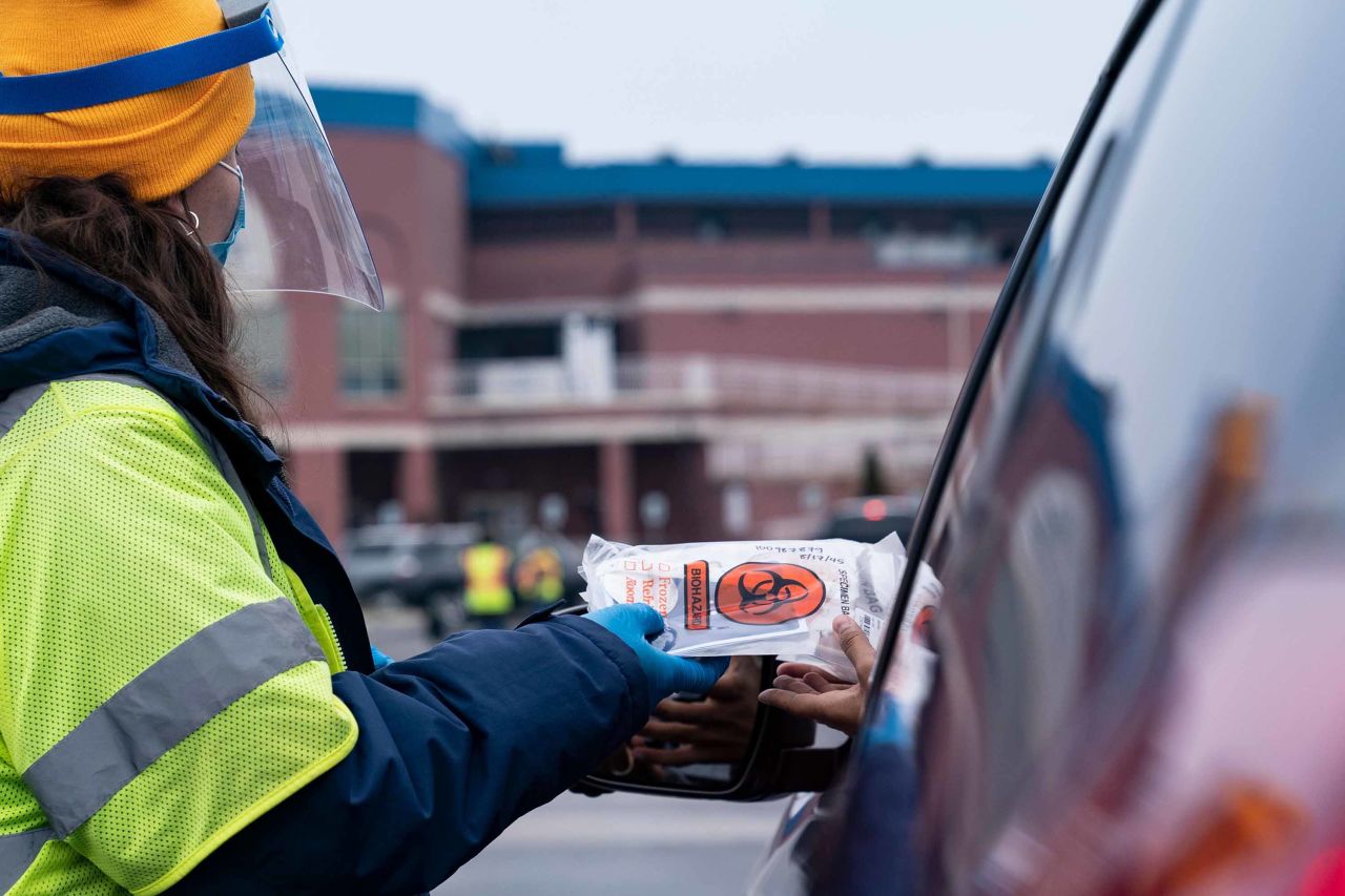 A sworker distributes a COVID-19 testing kit at a testing site in Wilmington, Delaware on December 21, 2020.