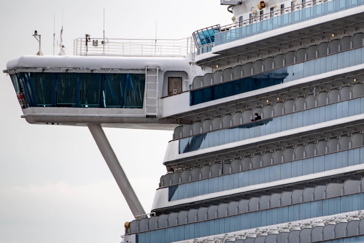 A passenger wearing a face mask looks out from a cabin of the Diamond Princess cruise ship quarantined at Daikoku pier cruise terminal in Yokohama on Thursday.