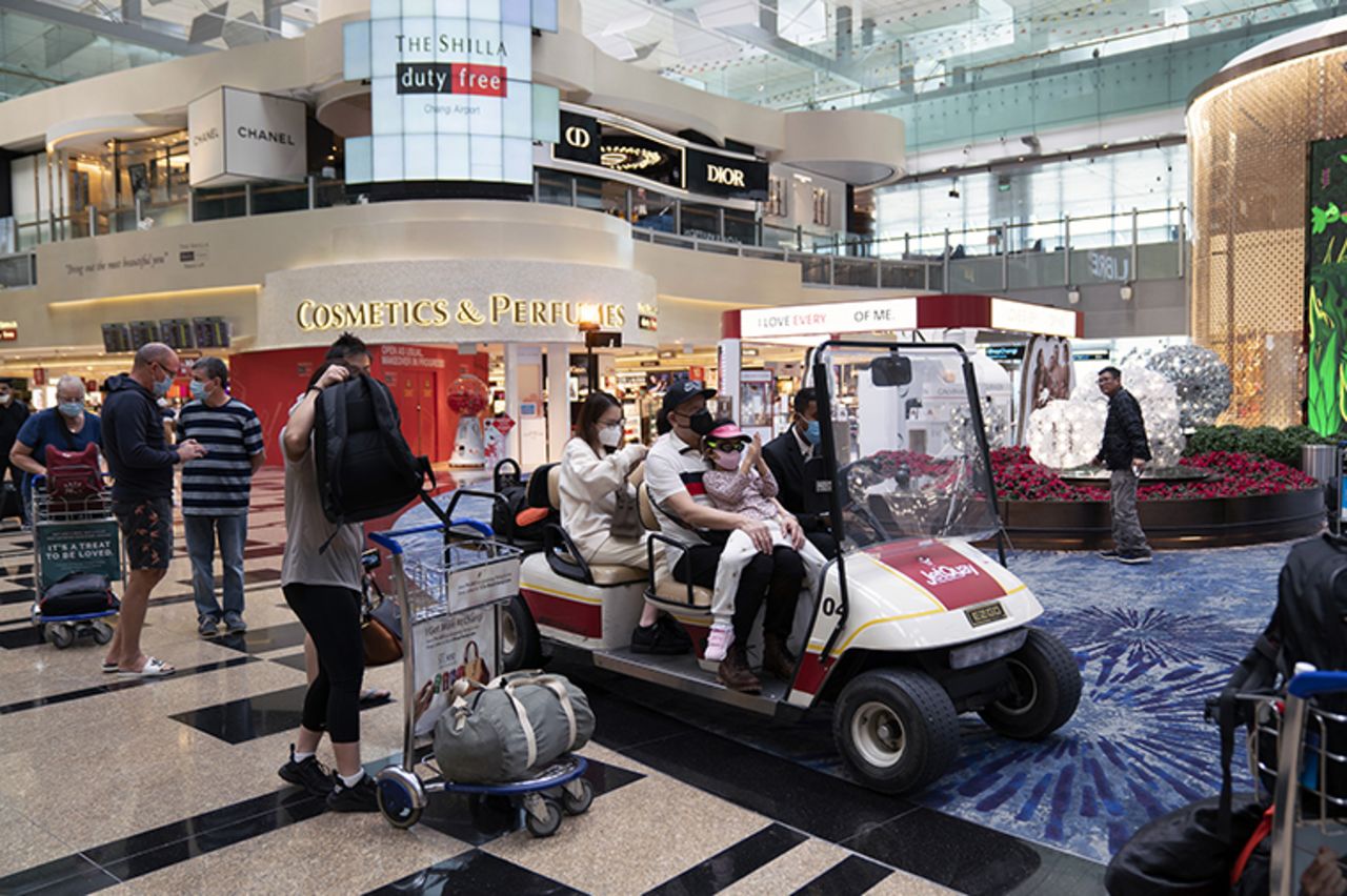 Travelers ride on a cart as they pass through a transit area at Singapore Changi Airport in Singapore, on Tuesday, March 17. 