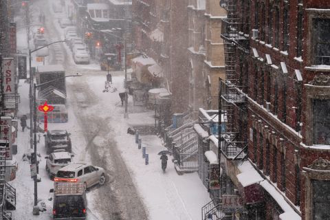 A pedestrian walks down a snow-covered sidewalk in New York on Monday.