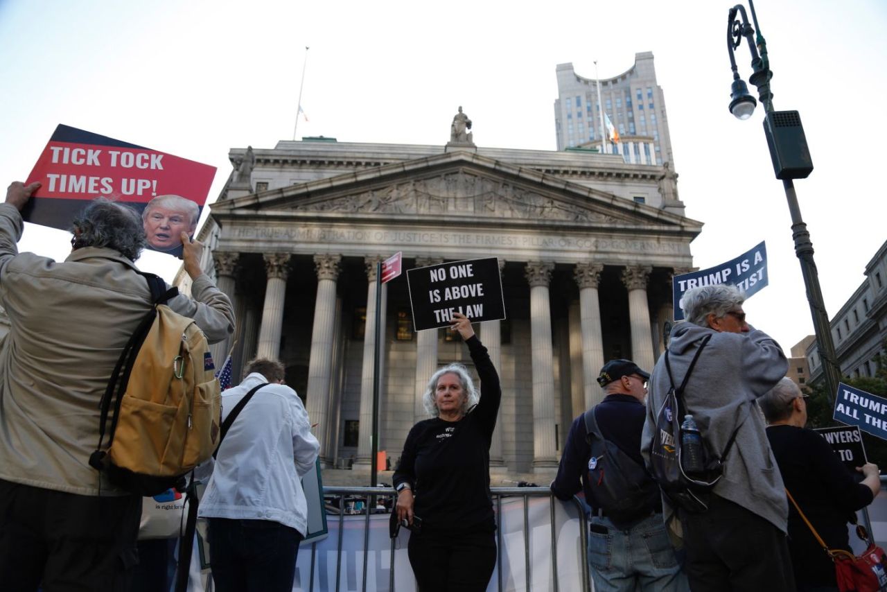 Demonstrators stand outside the court before the start of Trump's civil trial on Monday. 