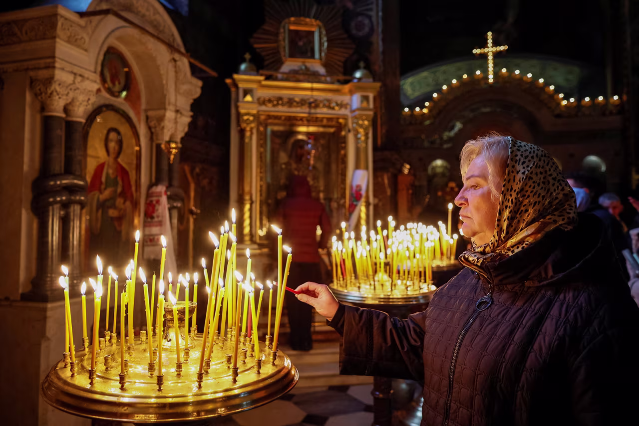 A woman lights a candle during Orthodox Easter service in Kyiv, Ukraine, on Sunday, April 16. 