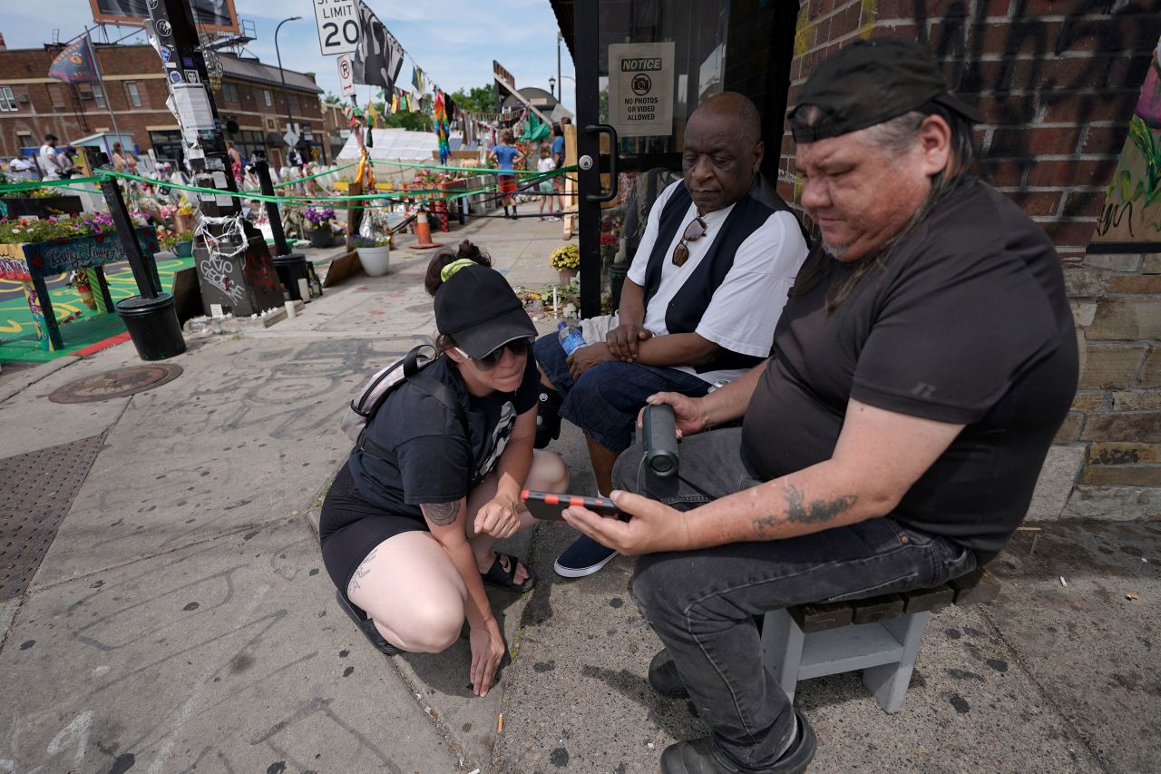 People watch the sentencing hearing on a cell phone at George Floyd Square in Minneapolis.