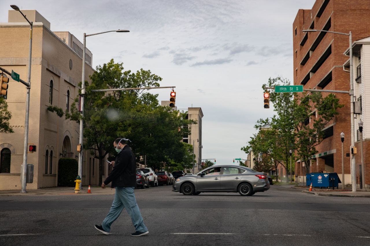 A pedestrian wearing scrubs and a mask crosses a street in Birmingham, Alabama, on April 28.