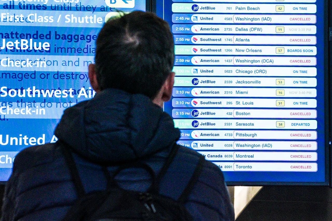 A passenger checks flight departures showing cancellations at Laguardia Airport, Friday December 23, in New York. 