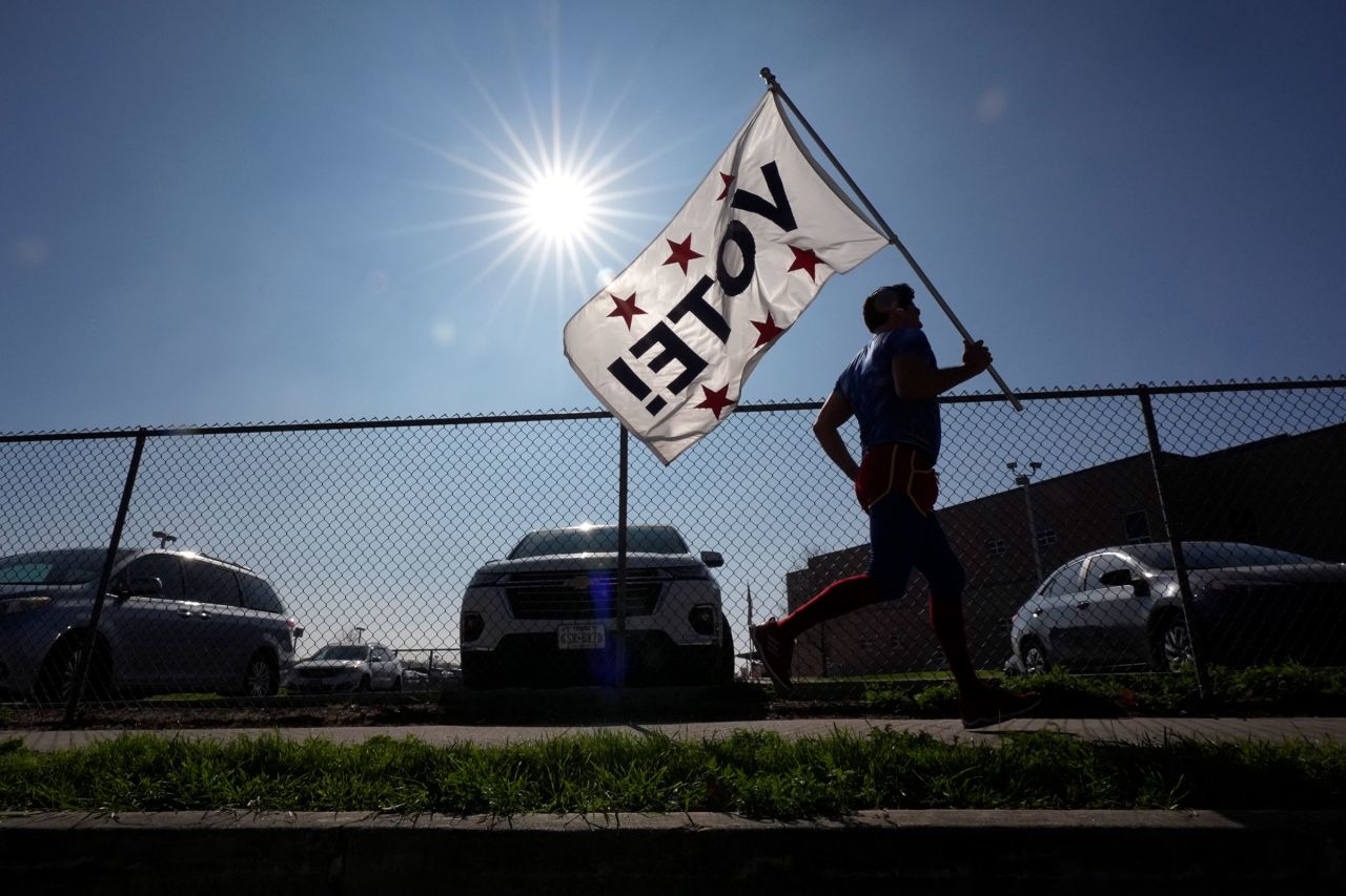 Dressed as Superman and holding a "Vote!" flag, Artist David Alcantar jogs past a polling site on Tuesday in San Antonio, Texas.