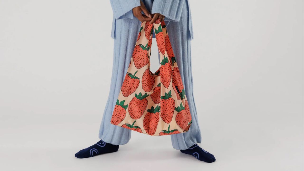 Woman holding strawberry-themed Baggu reusable bag