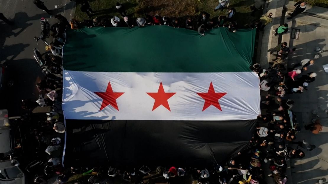 Personas flamean una bandera rebelde en Damasco el 9 de diciembre de 2024.