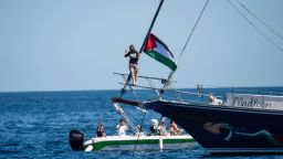 La activista climática Greta Thunberg permanece junto a una bandera palestina después de abordar el Madleen y antes de zarpar hacia Gaza con la Coalición de la Flotilla de la Libertad, saliendo del puerto siciliano de Catania el 1 de junio.