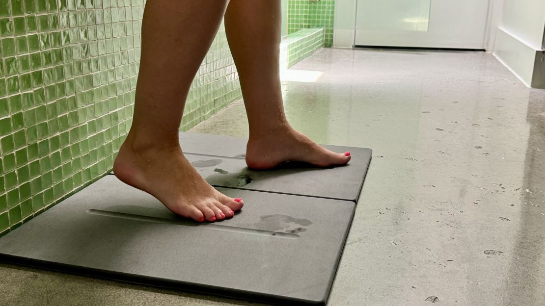 Feet walking off stone bath mat.