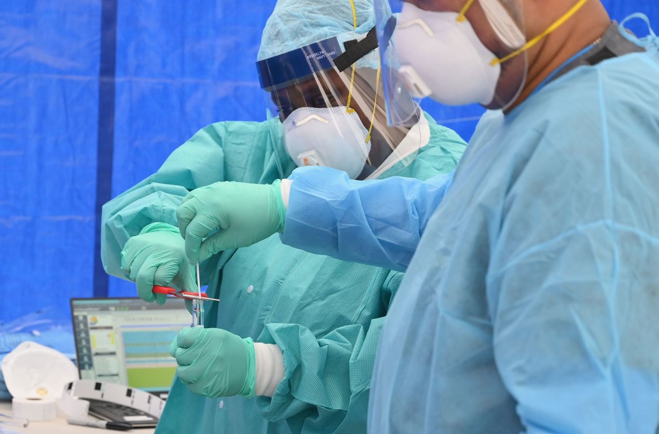 Health care workers place a coronavirus test swab into a tube at a testing site in the Brooklyn borough of New York City, on May 8.