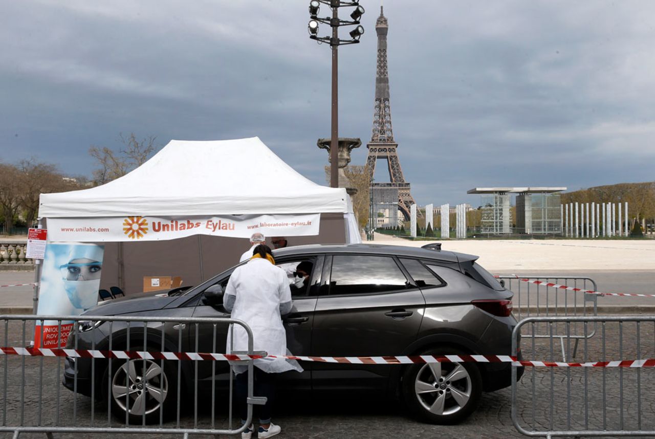 A medical biologist wearing a protective mask administers a nasal swab to a patient at a drive-through testing site for the coronavirus at the Champs de Mars next to the Eiffel tower on April 6, in Paris.