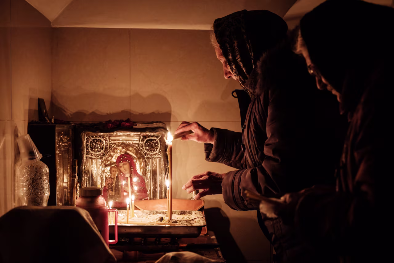 A woman lights a candle in the basement of the Church of All Saints as sounds and vibrations of shelling continue in Bakhmut, on Sunday.