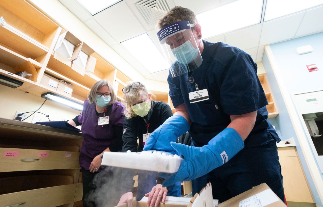 From left, UW Health pharmacy techs Amy Schultz, Susan Johnson and Nikolas Gardner unpack the first shipment of the Pfizer vaccine in Madison, Wisconsin, on Monday. 