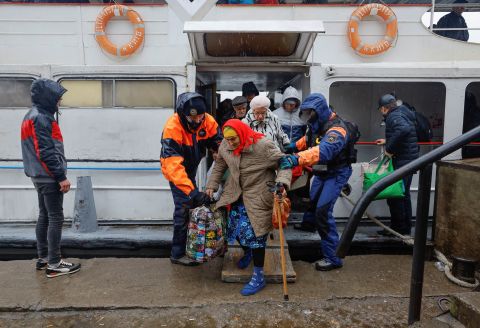 Civilians evacuated from the Russian-controlled city of Kherson walk from a ferry to board a bus heading to Crimea, in the town of Oleshky, Kherson Oblast, on October 23.